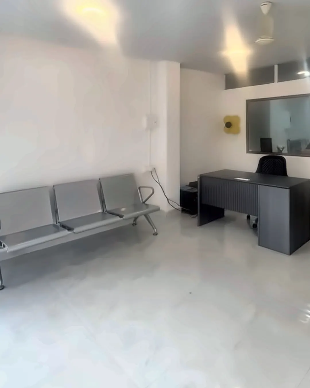Bright waiting area at Supriya Multispeciality Dental Clinic, with steel bench seating and the reception desk
